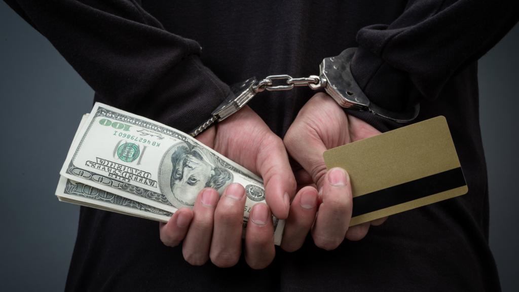 Persona esposada con dinero y una tarjeta: ciberdelincuencia y fraude
